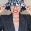 Mimi Condal indossando cappello a secchiello in pelliccia sintetica leopardata grigia.
