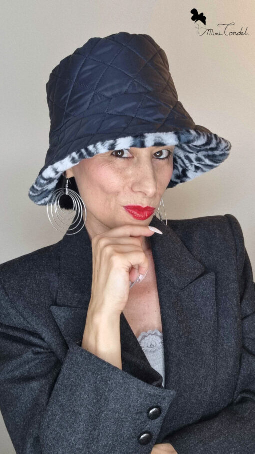Mimi Condal indossando cappello a secchiello in pelliccia sintetica leopardata grigia, lato reversibile trapuntato.