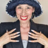 Mimi Condal indossando cappello a secchiello in pelliccia sintetica leopardata grigia, tesa sollevata.