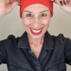 Mimi Condal mostrando come risulta indossato cappellino base rosso elasticizzato per nacondere la caduta capelli.