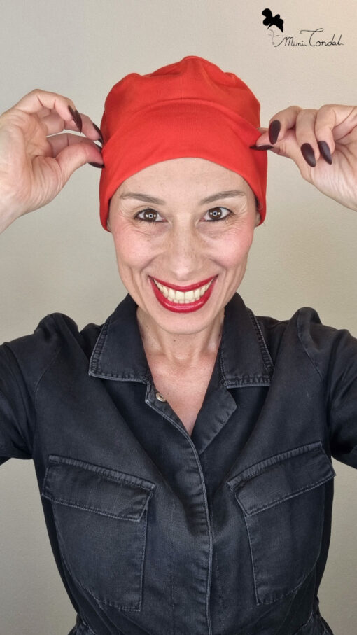 Mimi Condal mostrando come risulta indossato cappellino base rosso elasticizzato per nacondere la caduta capelli.